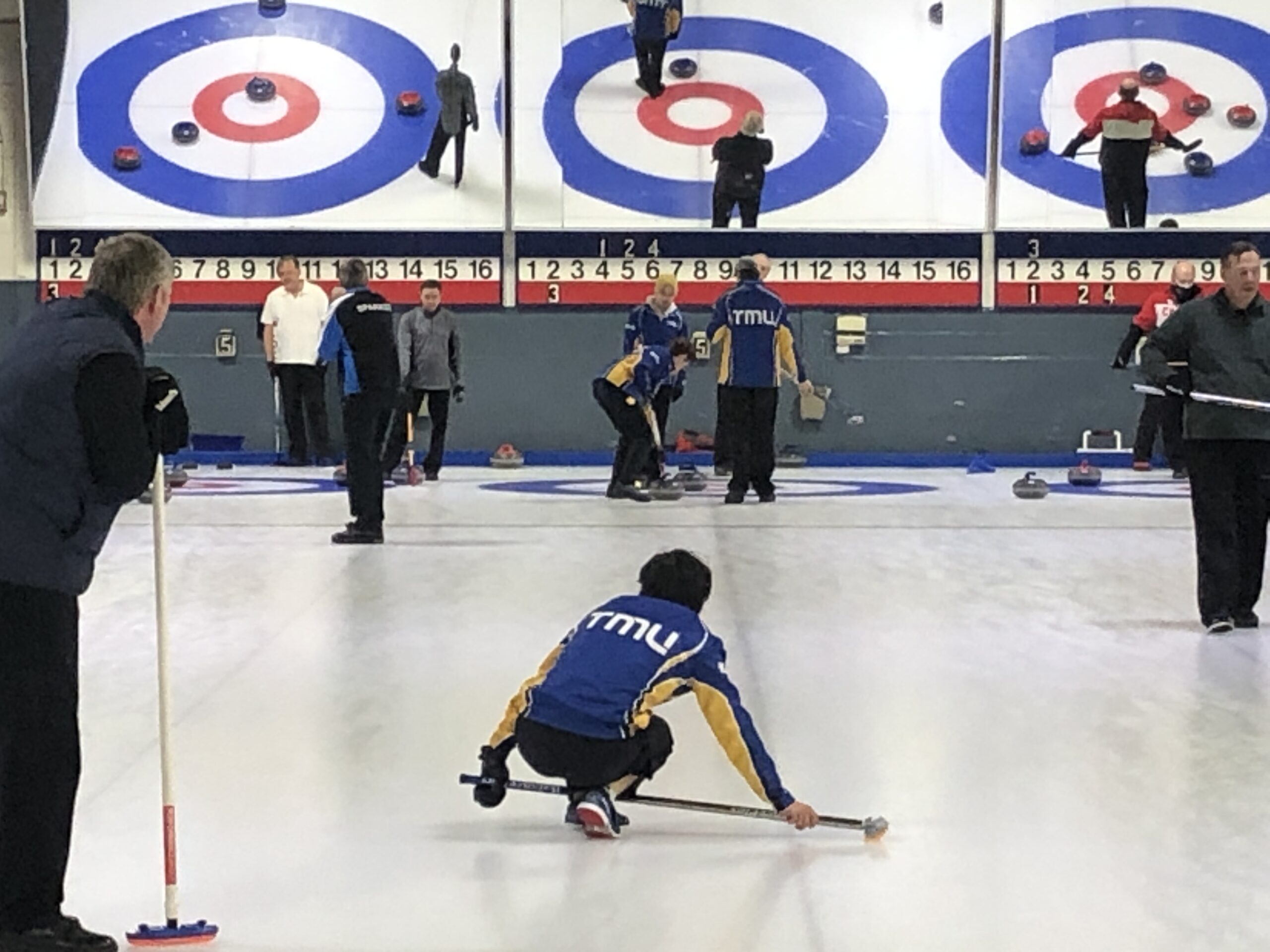 A TMU curler watches his shot from one knee