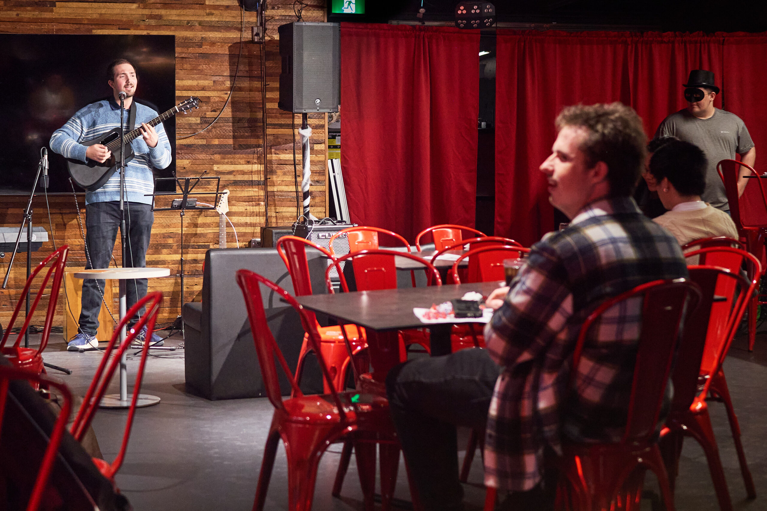 Daniel Shatil performs with a guitar on stage at The Met Campus Pub